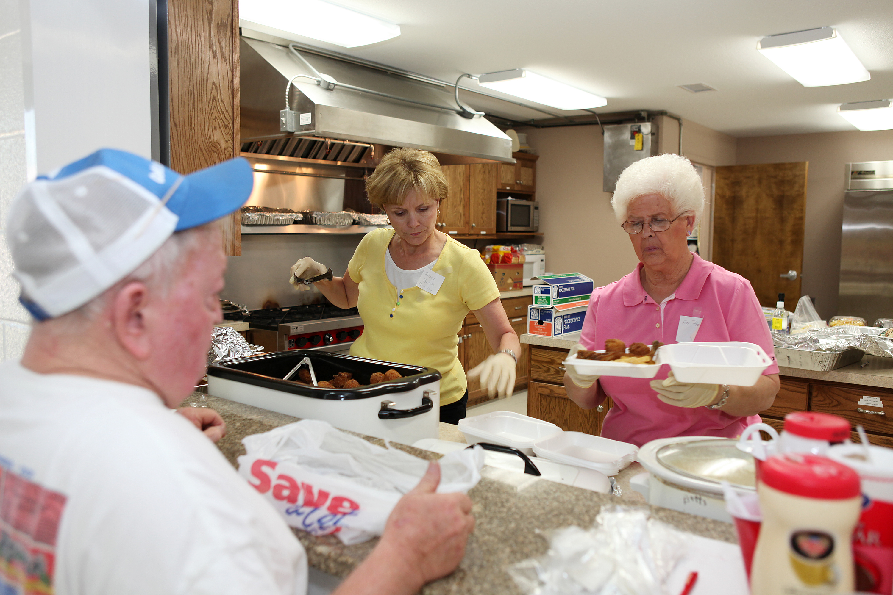 Volunteers serving a community meal in a church kitchen.
