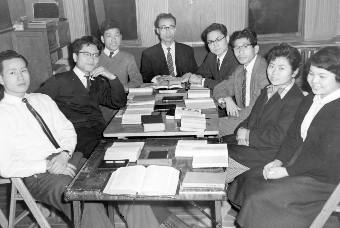 Adults gathered around a table for Bible study and conversation.